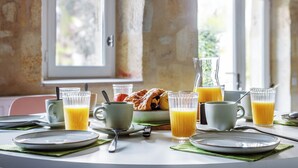 A breakfast setting with a table set for two, including plates, cups, a jug of orange juice, and a pastry. - 2-bedroom with pool near Saint Emilion (Guillac)