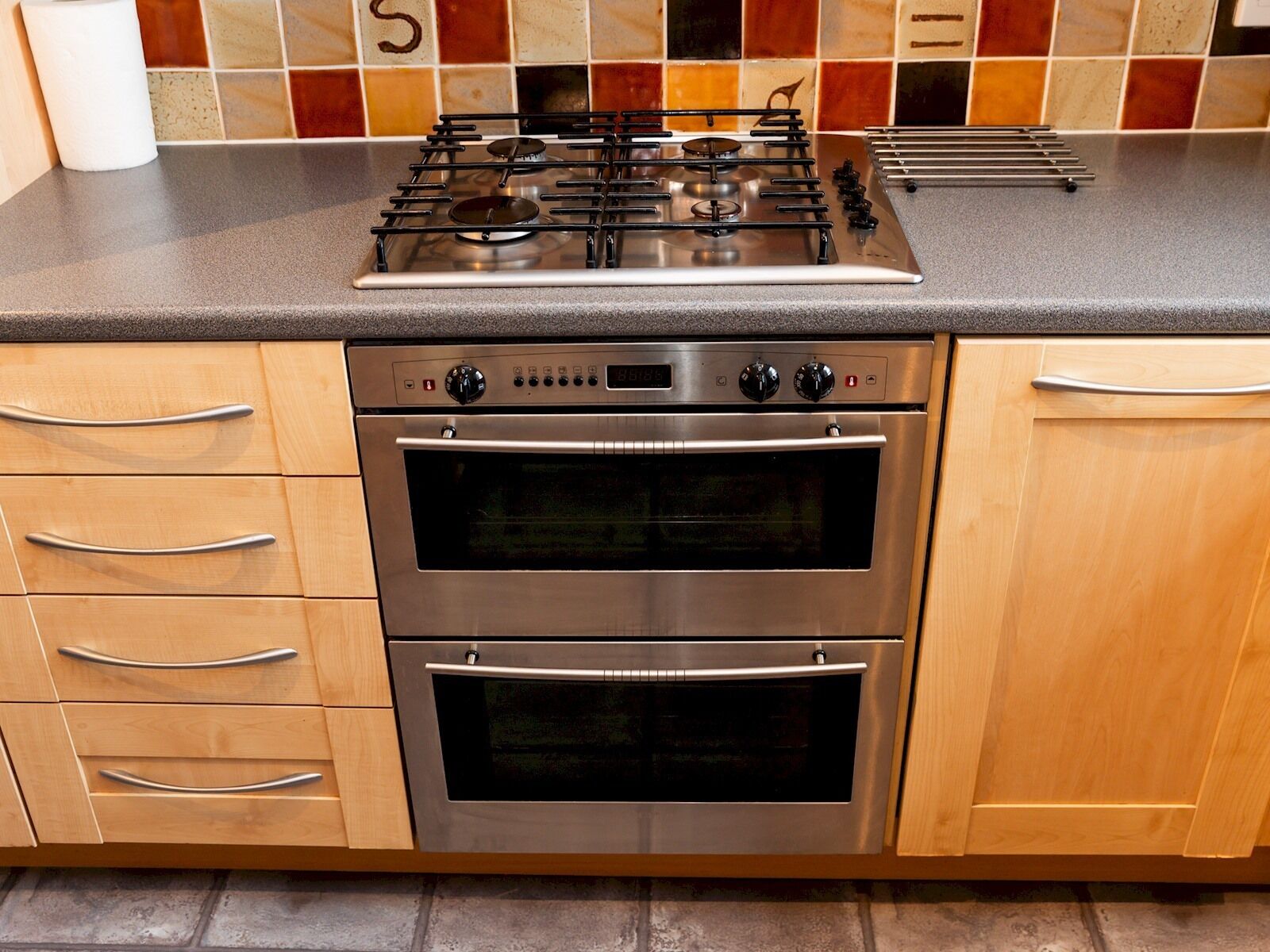 A kitchen with a gas stove, two ovens, and wooden cabinets.