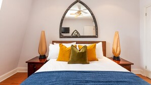 Ein Schlafzimmer mit einem großen Bett, einem Deckenventilator, einem Fernseher und zwei Lampen.