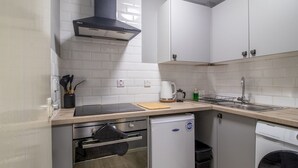 A compact kitchen with white cabinets, a black range hood, a built-in oven, a dishwasher, and a small refrigerator. - Pass the Keys | Cosy in Fabulous West End (Glasgow)