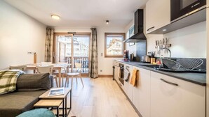 Et moderne køkken med en Bosch emfang, et spiseområde med bord og stole, samt en sofa med et lille bord.