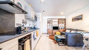 Et moderne køkken med en central ø, indbyggede hårde hvidevarer og et spiseområde med sofa og sofabord.