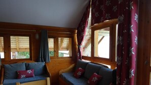 A cozy cabin interior with two wooden benches, a table, and large windows with curtains. - 300m from ski slopes, 3rd floor, swimming pool, balcony, tv, 46m², Valloire (Valloire)