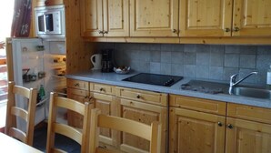 A kitchen with wooden cabinets, a microwave, a sink, and a coffee maker. - 300m from ski slopes, 3rd floor, swimming pool, balcony, tv, 46m², Valloire (Valloire)