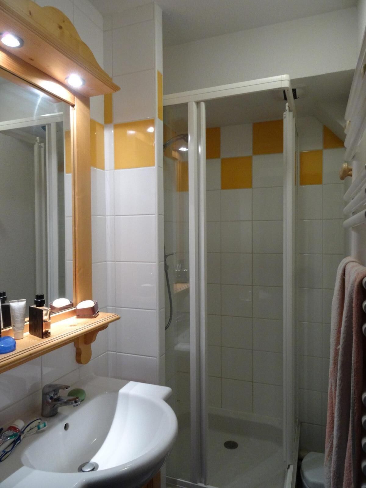 Un bagno con lavandino bianco, specchio e box doccia.