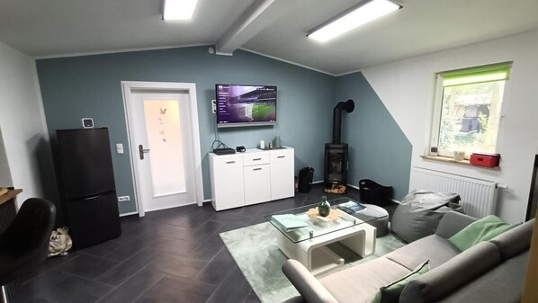 Ein modernes Wohnzimmer mit einer Couch, einem Couchtisch und einem an der Wand montierten Fernseher.