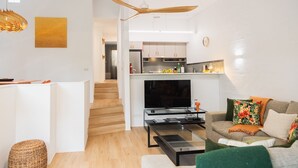 A modern apartment with a living room, kitchen, and staircase.