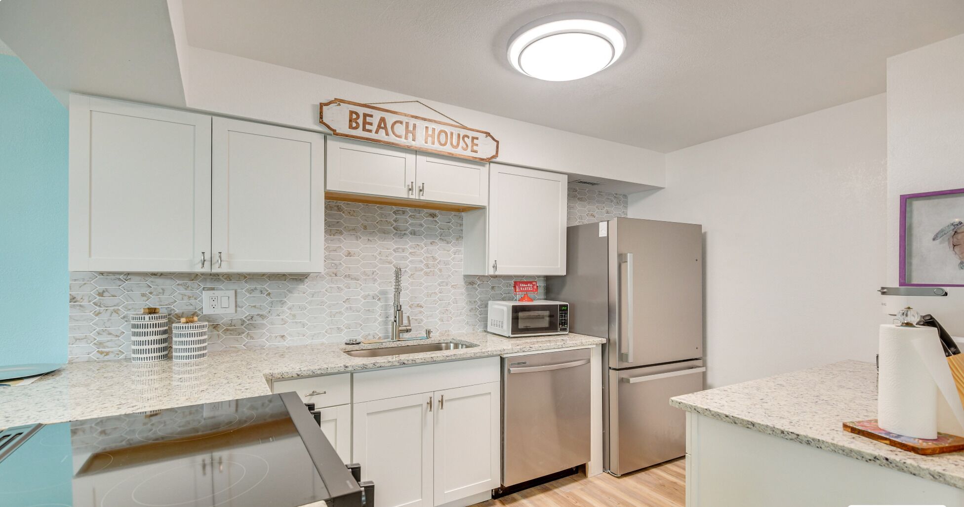 A kitchen with white cabinets, a microwave, a refrigerator, and a sink.