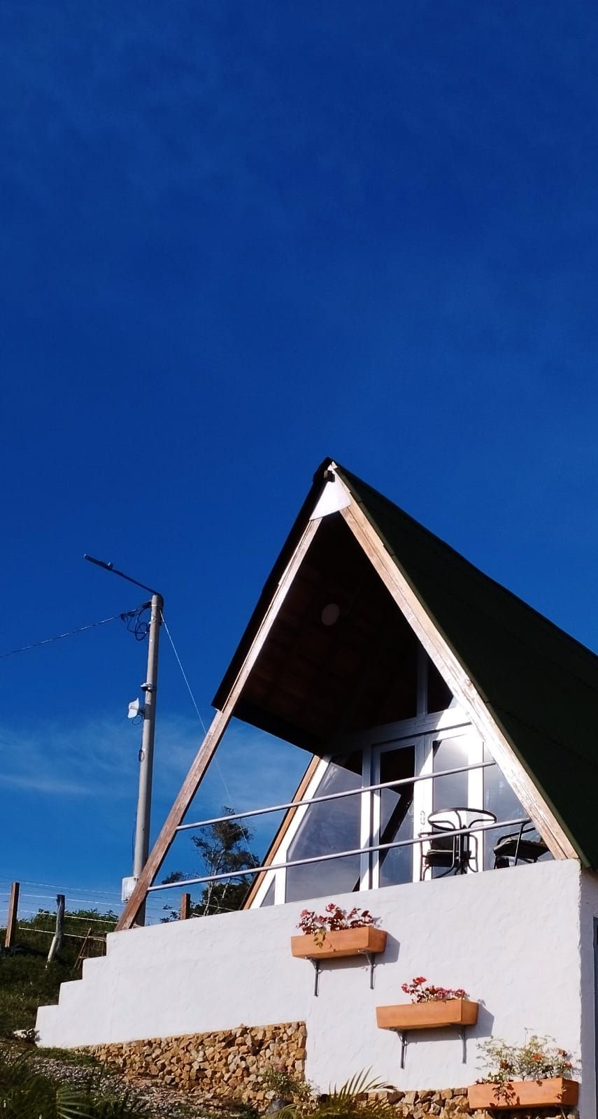 Un edificio bianco con tetto a punta e un balcone con posti a sedere all'aperto.