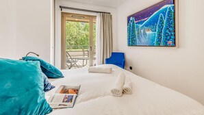 Ein Hotelzimmer mit Bett, Sessel, Tisch und einem Bild an der Wand.