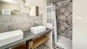 A bathroom with a large mirror, two sinks, a shower, and patterned tiles. - Authentic Cottage in Peaceful Setting with Private Terrace, Garden, and Wi-Fi (Beynat)