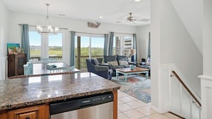 A spacious living area with a kitchen island, dining table, and seating.