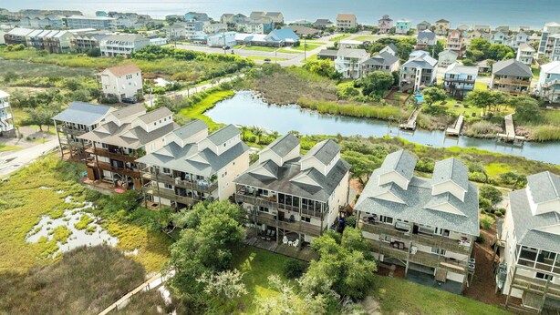 A coastal residential area with houses, a small lake, and a clear view of the ocean.