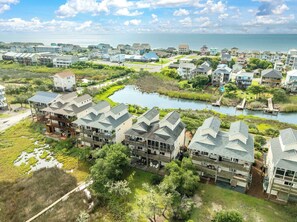 A coastal residential area with houses, a small lake, and a clear view of the ocean.