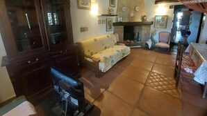Ein gemütliches Wohnzimmer mit Kamin, einer Couch, einem Fernseher und einem Essbereich mit Tisch und Stühlen.