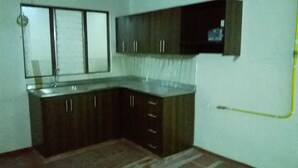 Una cocina con armarios de madera oscura, un lavamanos de acero inoxidable y un salpicadero de azulejos.