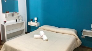 A bedroom with a bed, a nightstand, a mirror, and a blue wall with a crescent moon decoration.