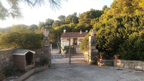 A gated property with a stone wall, a small brick structure, and a metal gate.