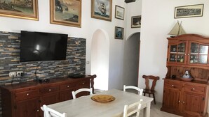 A dining area with a stone backsplash, wooden cabinets, and a television mounted above a counter.
