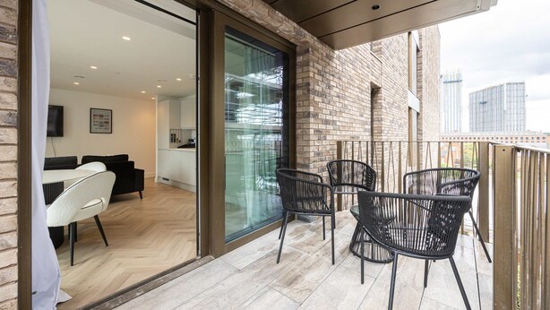Een moderne woonkamer met een glazen deur die leidt naar een balkon met zitplaatsen.