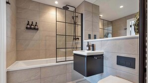 Ein modernes Badezimmer mit Duschkabine, Toilette und integriertem Waschbecken.