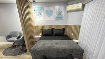 A bedroom with a bed, a nightstand, a chair, a fluffy rug, and wall art.