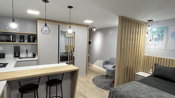Un dormitorio moderno con una cama, un escritorio con dos sillas, una mesita redonda y un televisor de pared.