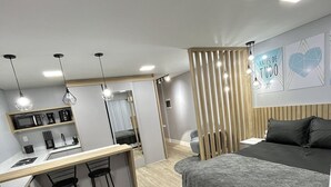 Un dormitorio moderno con cama, escritorio y kitchenette.