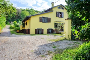 Une maison jaune avec une allée en gravier et un jardin.