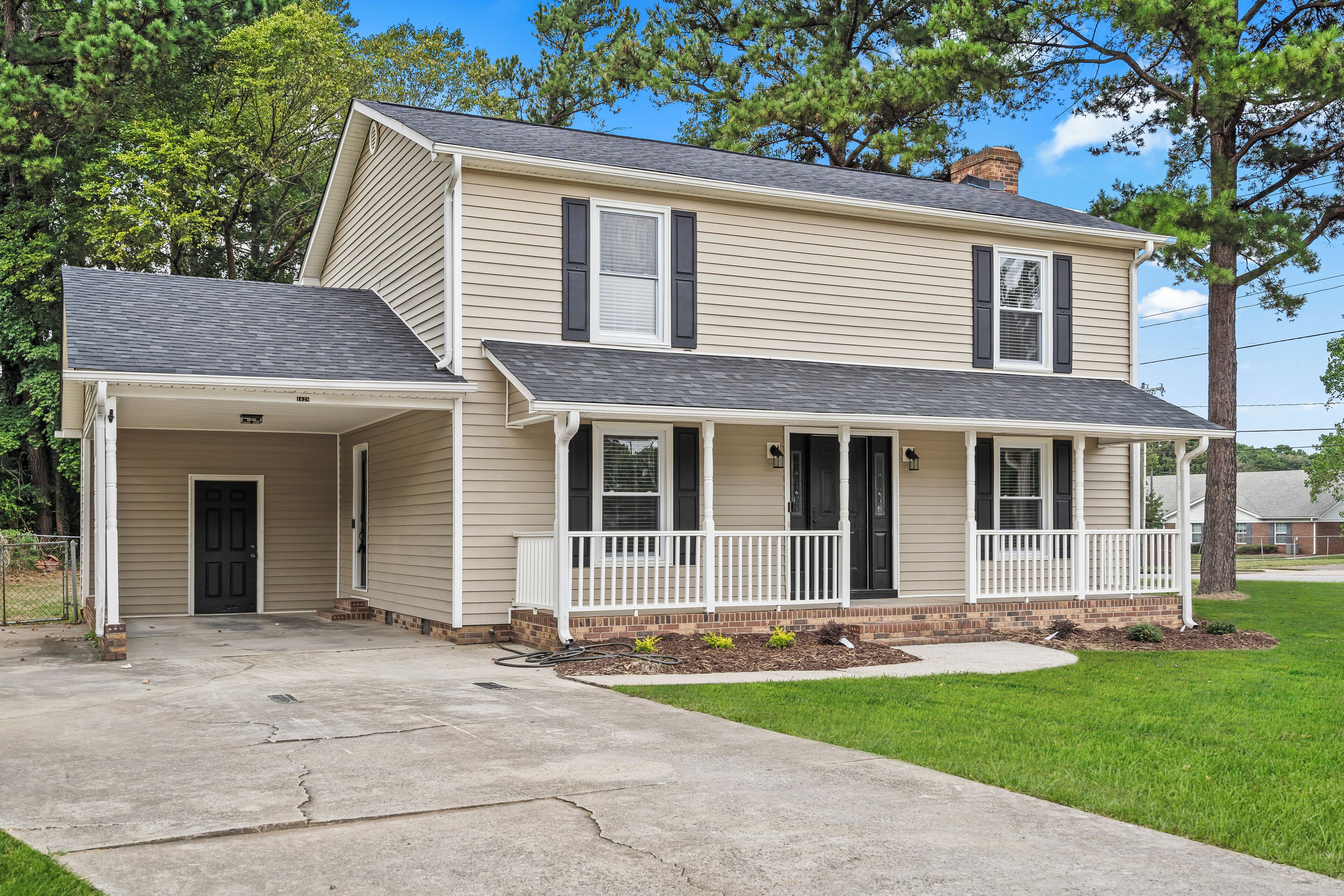 A two-story house with a front porch, a garage, and a well-maintained lawn.