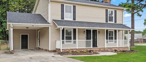 A two-story house with a front porch, a garage, and a well-maintained lawn.