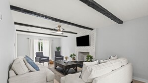 Un salon moderne avec une cheminée, deux canapés, une table basse et un téléviseur fixé au mur.