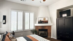 A bedroom with a large bed, a fireplace, a TV, and a wardrobe.