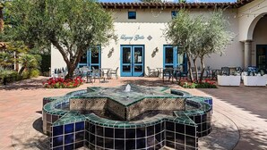 A building with a blue door and windows, a tiled fountain, outdoor seating, and greenery. - Stylish Desert King Room w/ Balcony + Pool View (La Quinta)