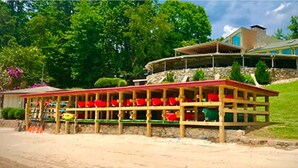 Un ristorante sulla spiaggia con un pontile in legno e sedie rosse, con vista sull'oceano.