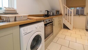 Une cuisine compacte équipée d’un lave-linge, d’un grille-pain et d’un four à micro-ondes.