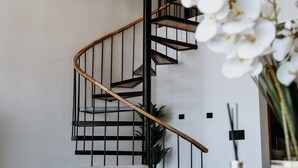Ein modernes Interieur mit einer Wendeltreppe, einem Holztisch und einem blauen Gegenstand sowie weißen Orchideen.