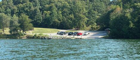 A lakeside parking area with vehicles and a dock extending into the water.