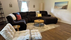 Ein Wohnzimmer mit einem Ecksofa, einem runden Couchtisch und einem gepolsterten Sessel.