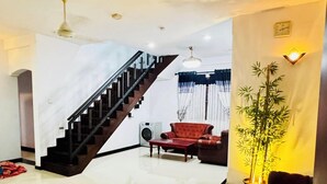 A spacious living area with a staircase, a red sofa, a coffee table, and a potted plant. - Feel at Home While You Travel (Tangalle)