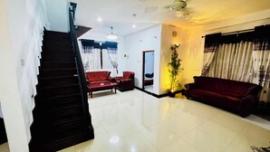 A spacious living room with a staircase, a red sofa, a dark brown sofa, and a potted plant. - Feel at Home While You Travel (Tangalle)