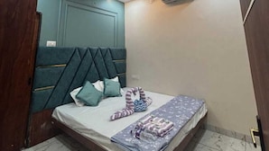 Et soveværelse med seng, ventilator og aircondition.
