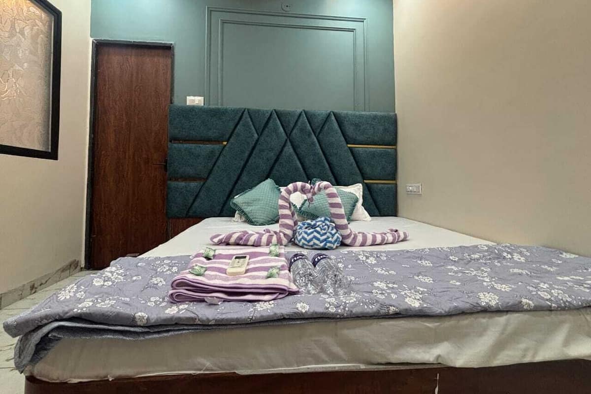 A neatly made bed with a patterned bedspread, pillows, and a striped blanket.