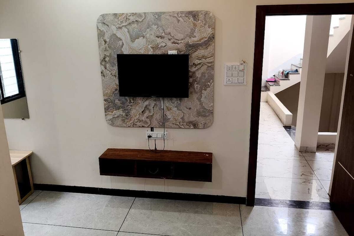 A modern living room with a marble wall-mounted TV, a wooden console table, and a tiled floor.
