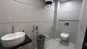 Et badeværelse med en hvid vask, toilet og bruseområde.