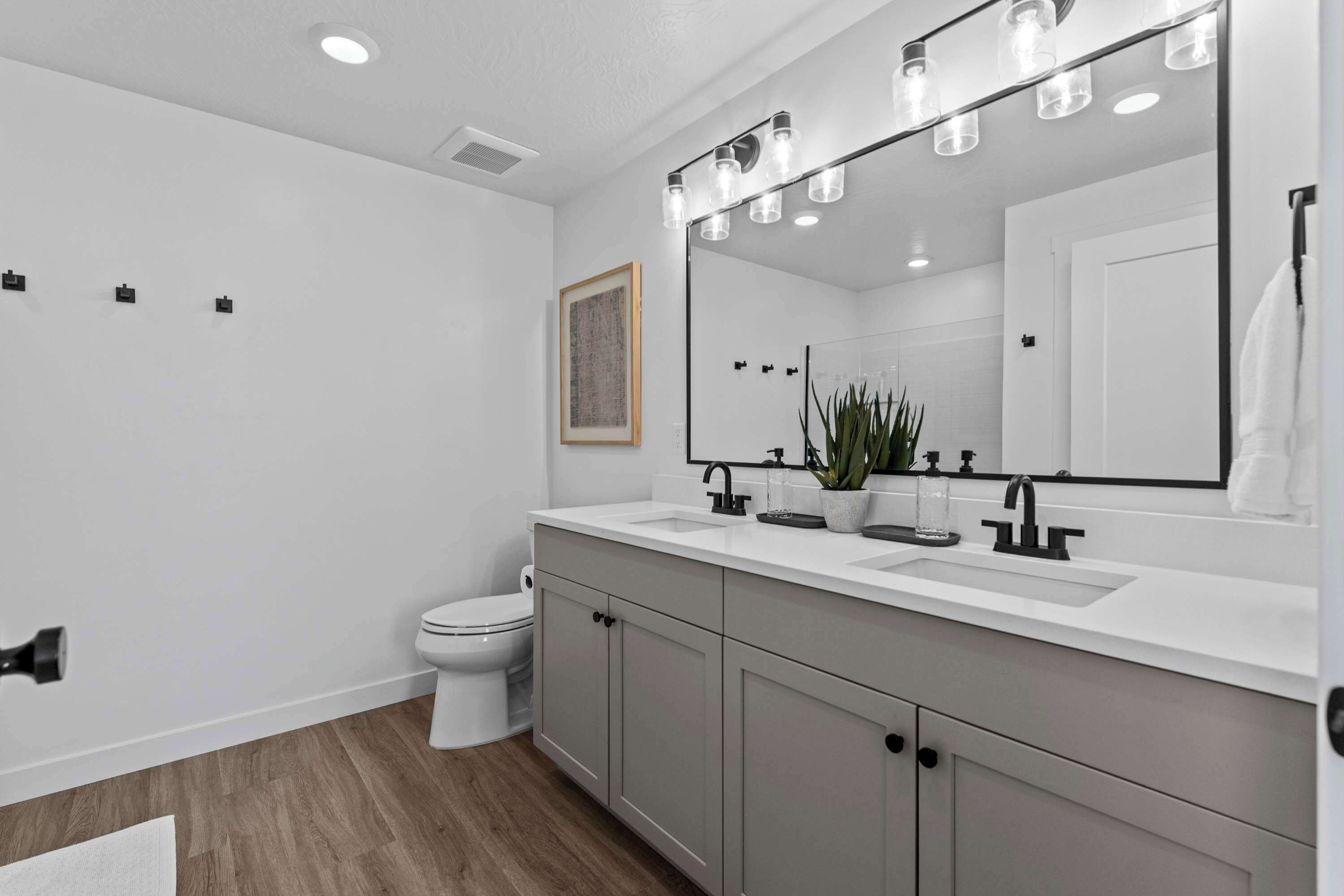Un baño moderno con un lavamanos blanco, un espejo grande y un inodoro.