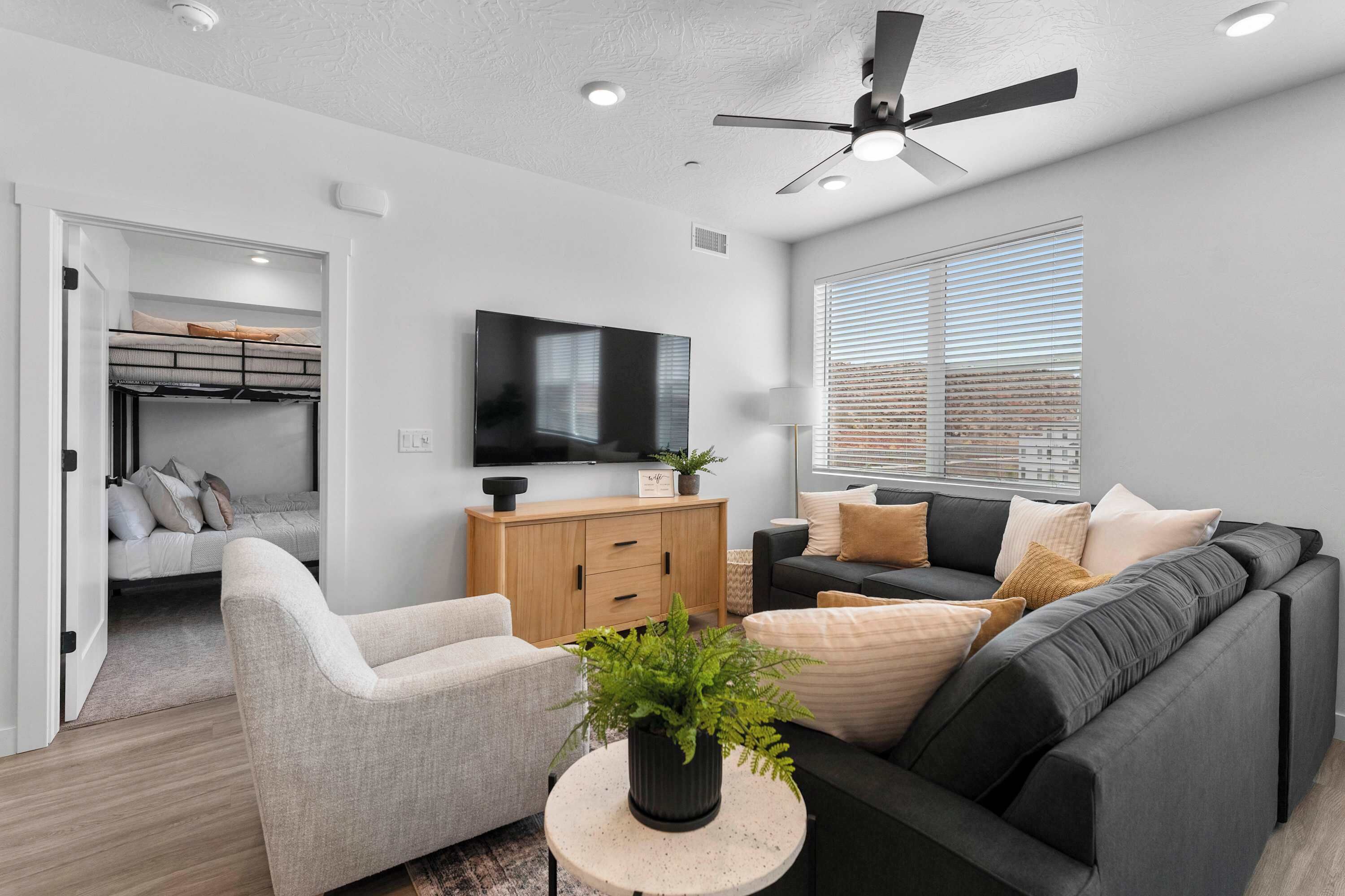 A modern living room with a sofa, armchair, and a television on the wall.