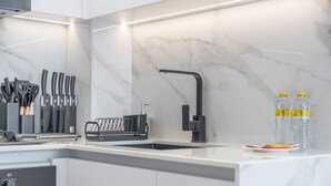 Une cuisine moderne avec un dosseret en marbre blanc, un robinet noir et un bloc à couteaux.