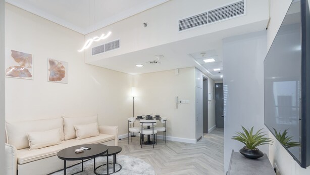 A modern living room with a sofa, coffee table, and dining table. - Vibrant Studio in JLT Sleeps 4 With Lake Views (Dubai)