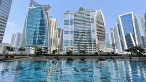 A modern urban setting with a large pool area surrounded by high-rise buildings. - Cosy Unit in Business Bay Sleeps 2 With Canal View (Dubai)